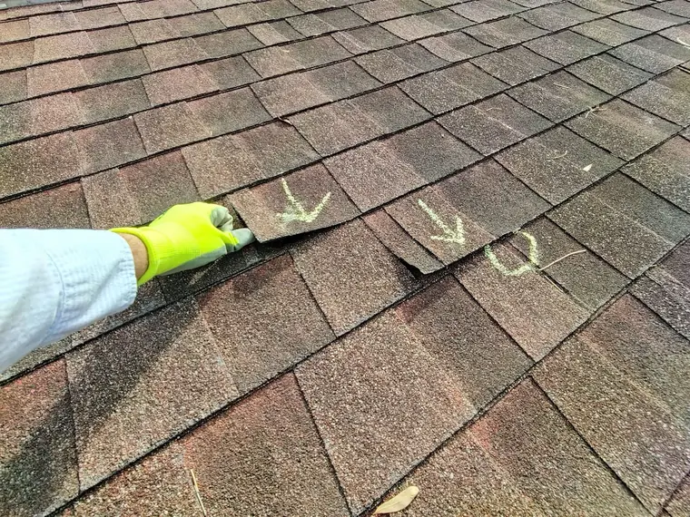Row of lifted shingles marked with chalk arrows