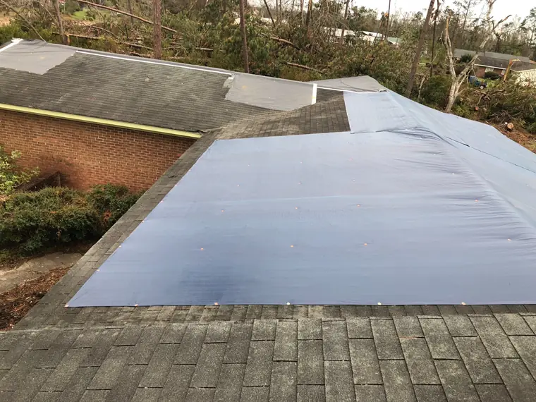 Hurricane-damaged roof sealed with a fastened tarp
